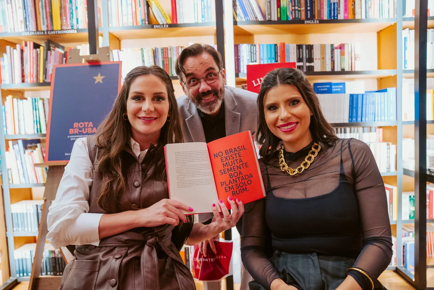 Sara Stofela e Monique Ferreira com leitor segurando o livro Rota BR-USA na Livraria da Travessa